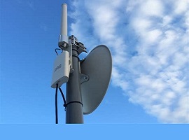 photo of an AREDN transceiver mounted on a tower and a microwave dish